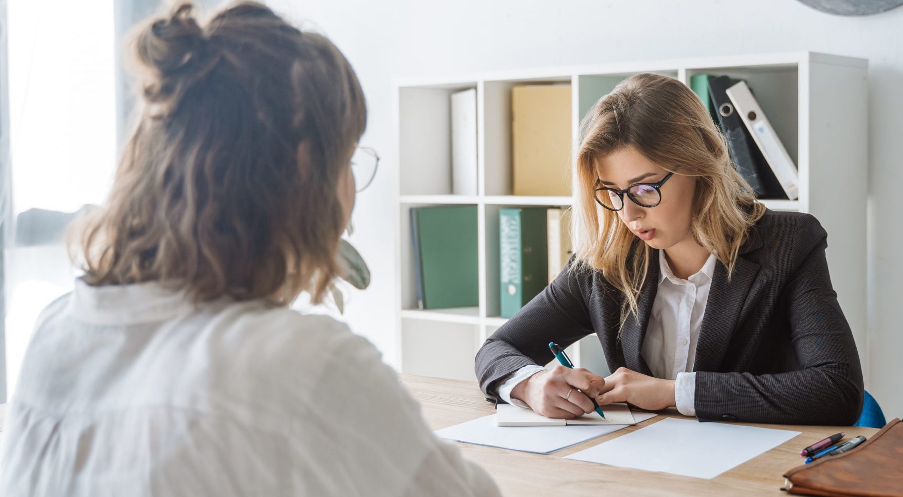 Young female candidate is interviewed by employer businesswoman